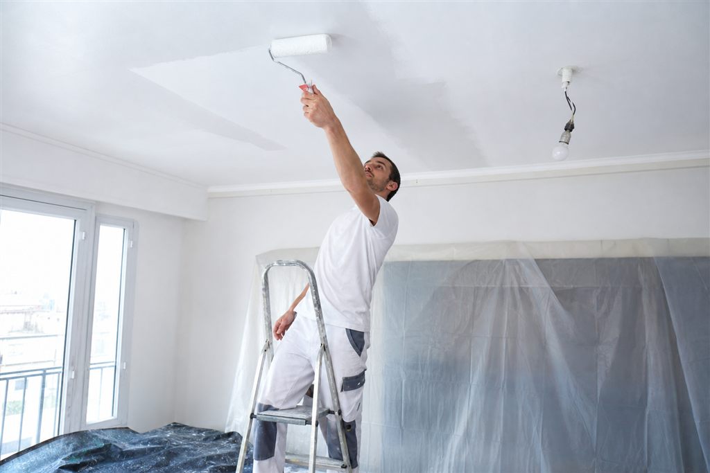 Artisan repeignant un plafond remis à neuf après un dégât des eaux